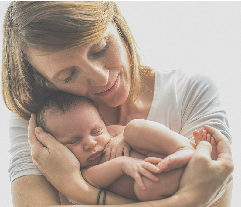 Mother gently holding a sleeping newborn baby